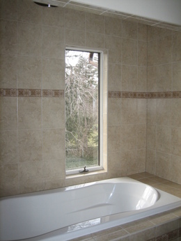 Detailed tile work in bathroom. Pictured here is a rainfall shower over large bath.